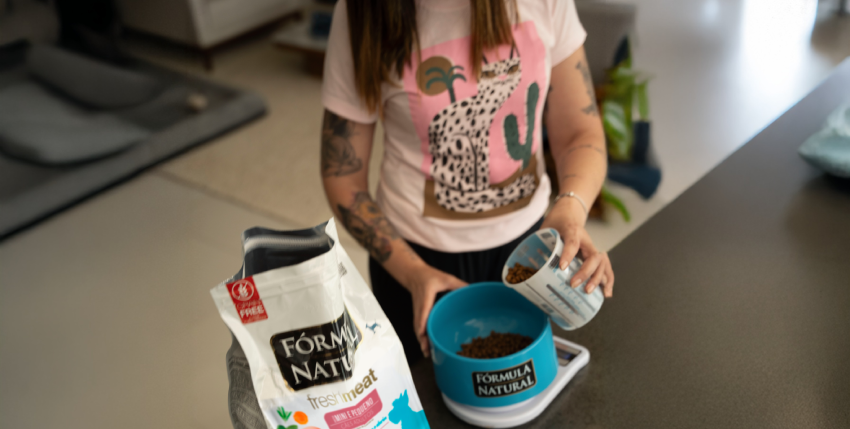 Mulher colocando ração na tigela Formula Natural para seu cão